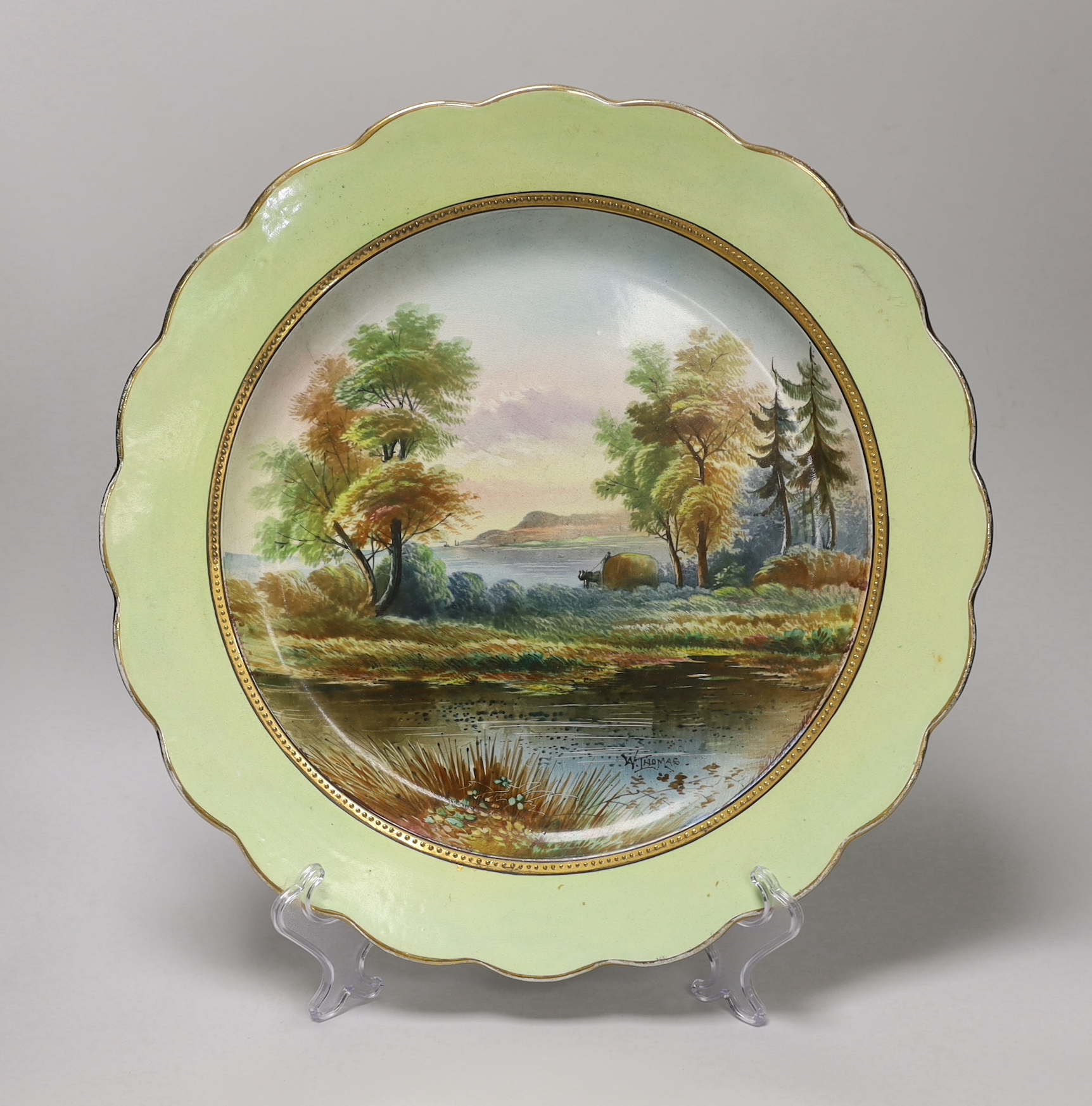 A mid 19th century English pottery charger painted with a coastal landscape under a light green border signed W. Thomas, indistinct factory and registration mark 39cm in diameter
